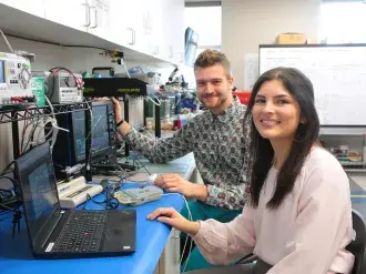 Employees sit by a laptop testing electronic devices