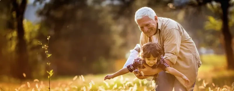 an elderly man picks up a young boy
