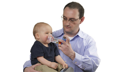 AeroChamber Plus Flow Vu Chamber orange child mask in use by baby helped by father