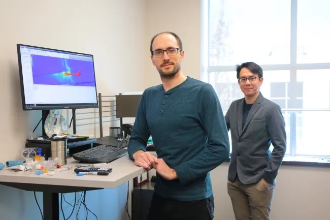 Employees stand in front of computer