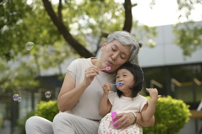 A grandmother blowing bubbles with her grand daughter