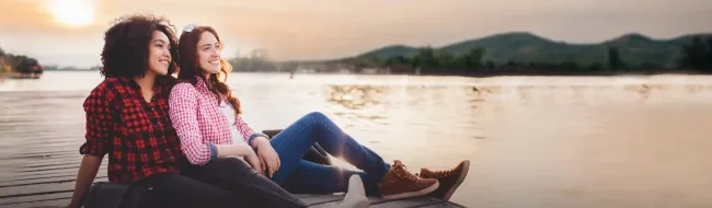 Two women relaxing on a dock by the water