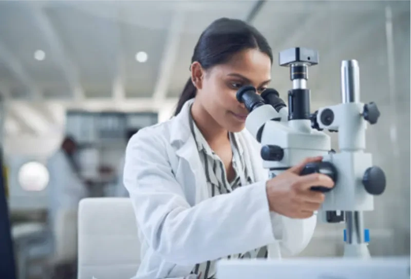 A lab technician looking through instrument