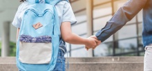 child with backpack walking into school